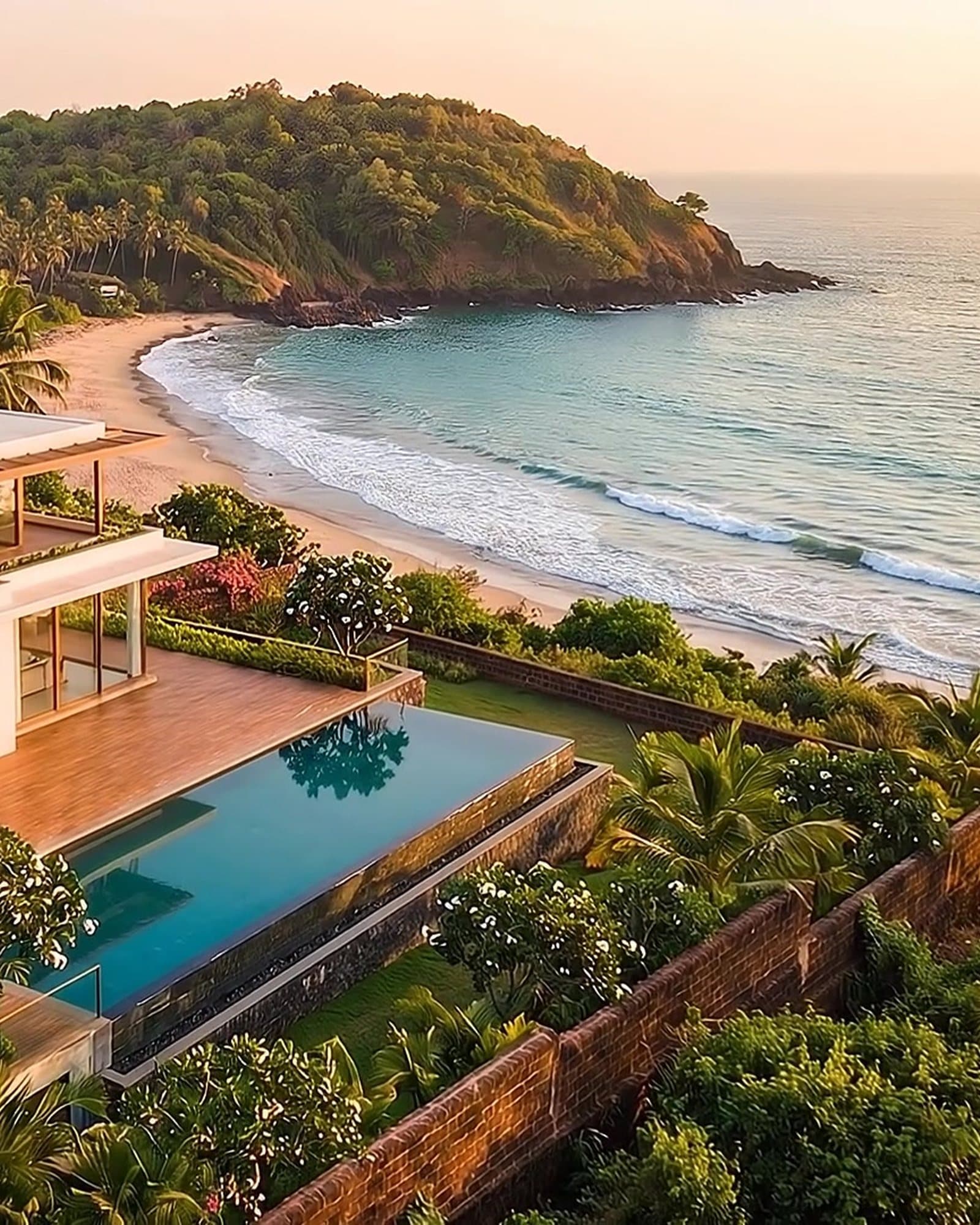 The quiet sandy bay below the villa, framed by palms and the headland