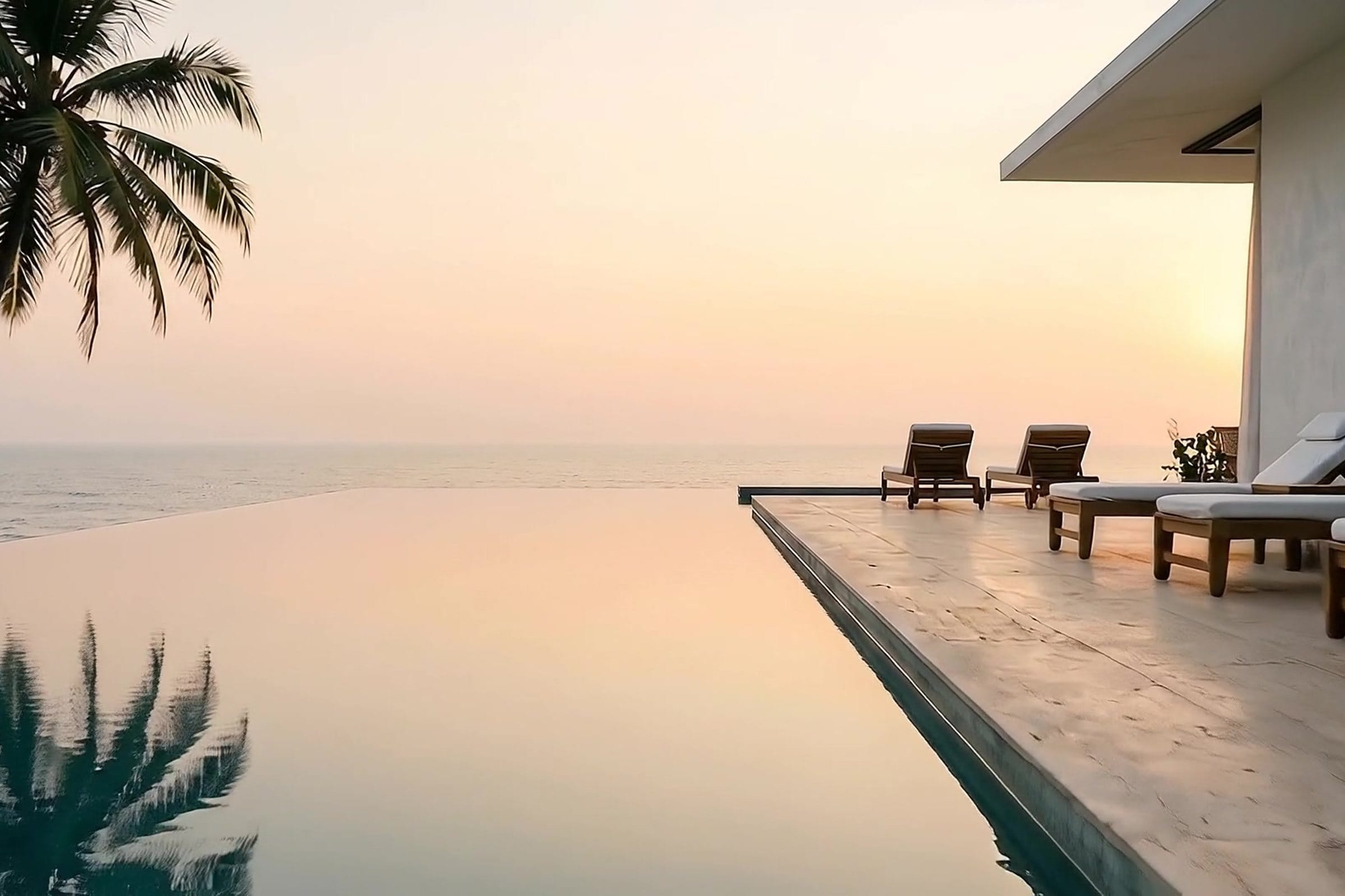 The infinity pool edge merging with the Arabian Sea at sunset